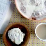 Cherry pineapple upside down cinnamon roll on a plate with a cup of coffee and a book.