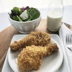 Low carb baked chicken legs on a white plate with salad on the side