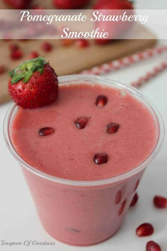 Pomegranate Strawberry Smoothie with a strawberry on the side and pomegranate seeds on top. 