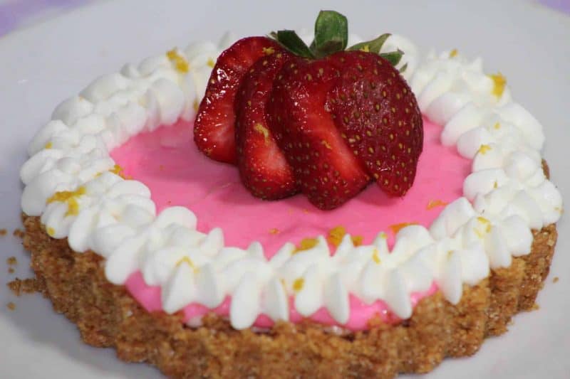 Mini No-Bake Berry Cheesecake with a graham cracker crust topped with strawberries and whip cream