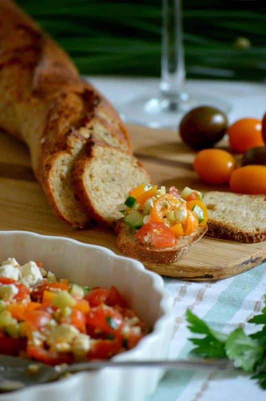 Feta, Cucumber & Tomato Appetizer in a tart pan with a baguette in the background. 