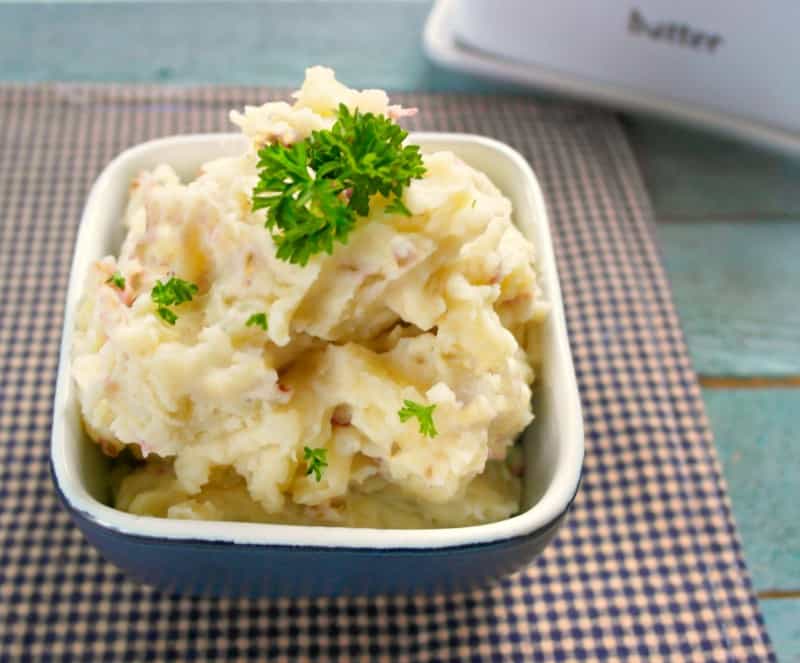 slow cooker mashed potatoes in a blue bowl with parsley