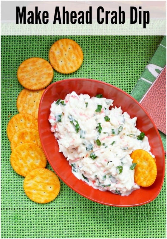 Cold crab dip recipe in a football shaped bowl with Ritz crackers on a green mat.