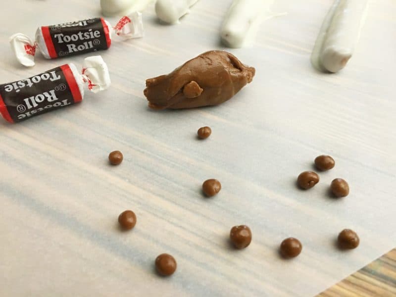 Tootsie Rolls being rolled into little balls for eyes for a fun Halloween dipped pretzel recipe. 