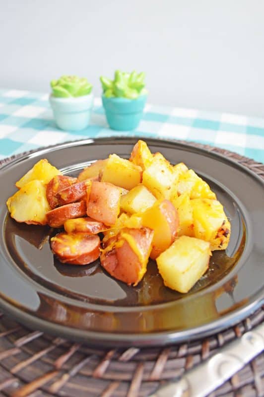 Cheesy sausage and potatoes on a black plate