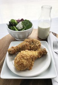 Low carb baked chicken legs on a white plate with salad on the side