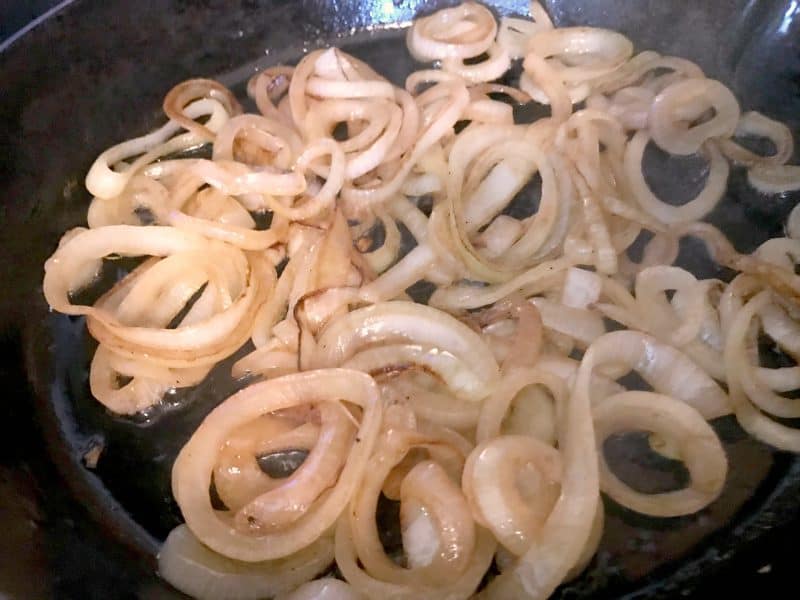 Onions being caramelized in a cast iron skillet for easy french onion chicken