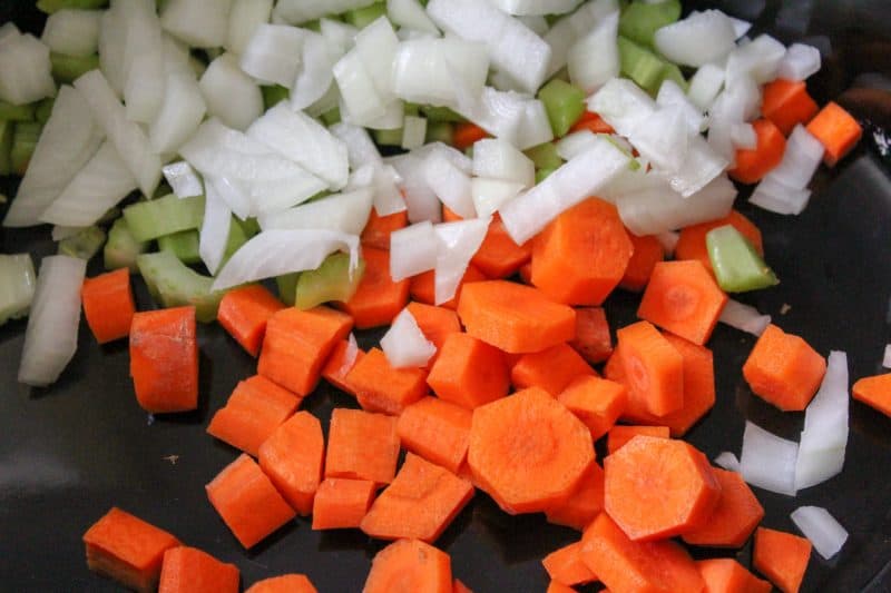 Diced carrots, onions and celery combined in a pan for a homemade beef stew recipe. 