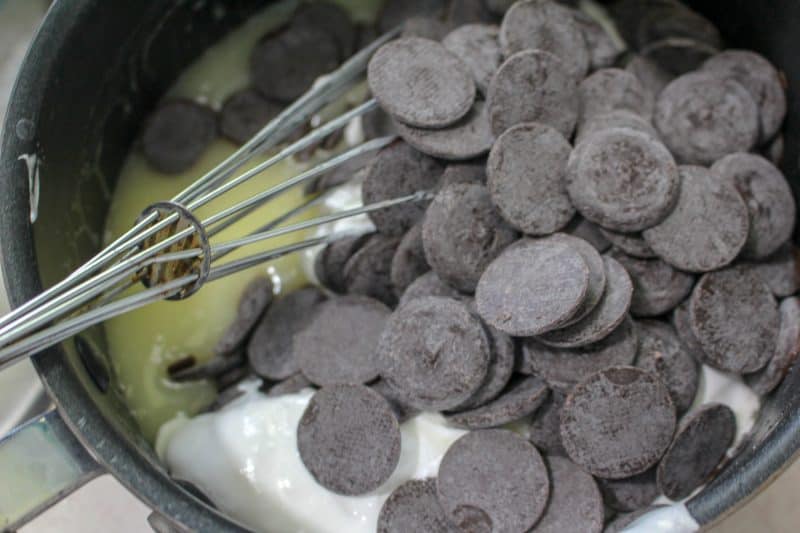 Chocolate chips, marshmallow fluff and whipping cream with a whisk ready to make homemade fudge. 