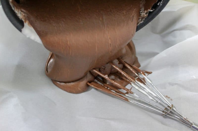 Easy fudge recipe being poured into a pan with parchment paper. 