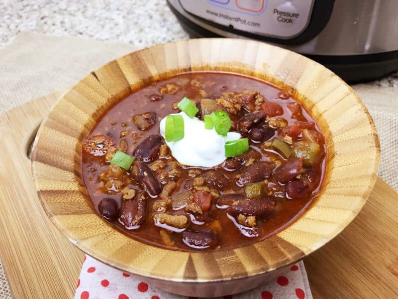 Ground beef chili made in the Instant Pot topped with sour cream and green onions. 