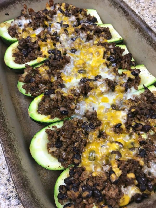 Zucchini taco boats on a baking sheet, topped with cheese. 