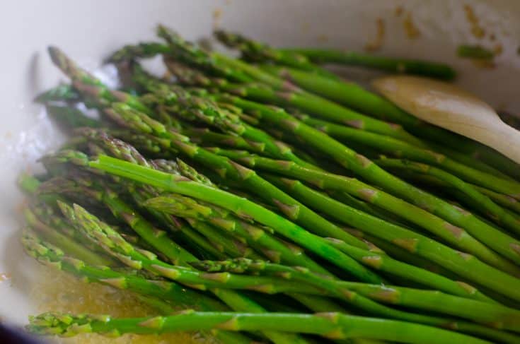 Steamed asparagus sprinkled with seas salt in a pan.