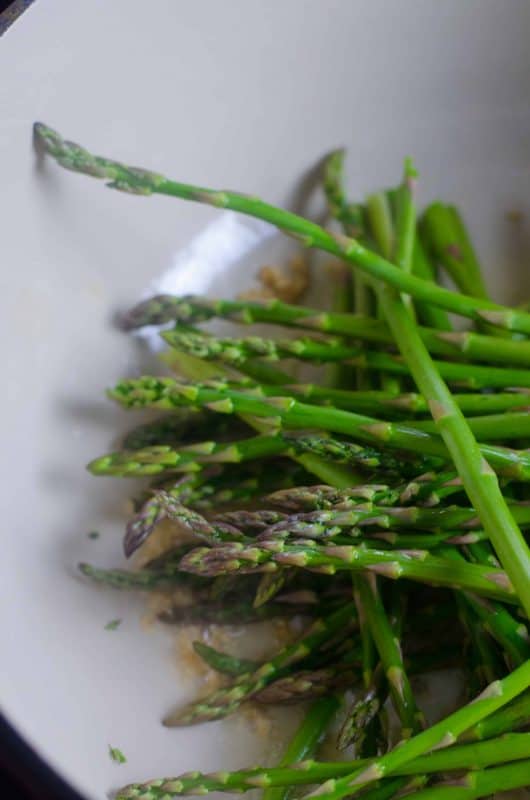 Steamed asparagus sprinkled with seas salt in a pan. 