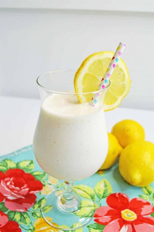 Frosted Lemonade in a wine glass and sliced lemons.