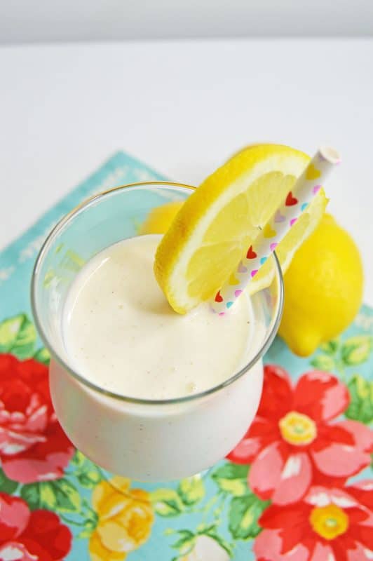 Frosted Lemonade in a wine glass and sliced lemons.